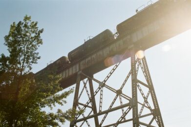 view looking up at rail road tracks trestle with train going across